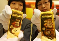 Dos mujeres chinas con lingotes de oro en las manos