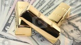 Lingotes de oro encima de billetes de dólares